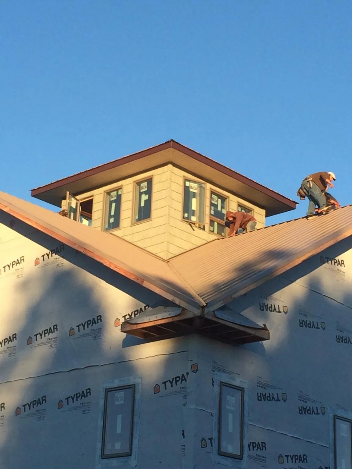 Roofers working around a rooftop cupola on a new metal roof at sunset — Roof Waterproofing in Cummings by Roofing Brothers